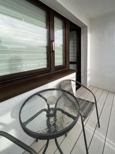 balcón con mesa de cristal y silla en Apartament Iga, en Opole