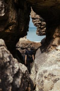 a man walking through a cave through a rock formation at João Jungle in Açafora