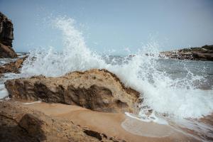 a wave crashing against a rock on the beach at João Jungle in Açafora