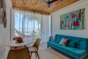 ein Wohnzimmer mit einem blauen Sofa und einem Tisch in der Unterkunft Apartamentos Orla Itacaré - Casa Flor in Itacaré