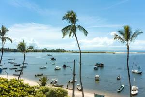 eine Gruppe von Booten in einem Wasserkörper mit Palmen in der Unterkunft Apartamentos Orla Itacaré - Casa Flor in Itacaré