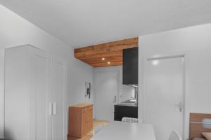 a kitchen with white walls and a wooden ceiling at Studio cosy au centre de Crans-Montana in Crans-Montana +18 photos