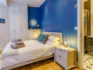 ein Schlafzimmer mit blauen Wänden und einem Bett mit einem Nachttisch in der Unterkunft Luxury studio above the stunning Tenby Harbour in Tenby