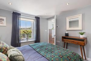 1 dormitorio con cama, mesa y ventana en Luxury three bedroom coastal cottage, en Cardigan