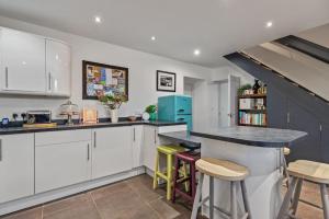 una cocina con armarios blancos y una barra con taburetes en Luxury three bedroom coastal cottage, en Cardigan