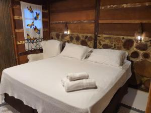 uma cama com duas toalhas em cima em Chalés Catavento em Maresias