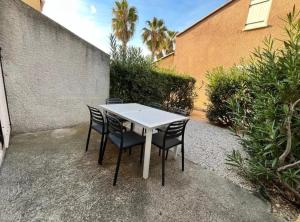 een witte tafel met vier stoelen naast een gebouw bij Bel appartement avec place de parking privée, piscines in Vendres