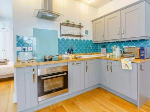 eine Küche mit weißen Schränken und einer blauen Wand in der Unterkunft Luxury studio above the stunning Tenby Harbour in Tenby