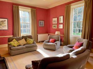 a living room with red walls and couches and windows at Marlacoo House Luxury Georgian home in Portadown