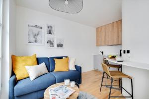 ein Wohnzimmer mit einem blauen Sofa und gelben Kissen in der Unterkunft Amazing Residence Cremieux Gare de Lyon in Paris