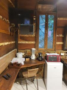 a kitchen with a table and a microwave and a window at Chalés Catavento in Maresias