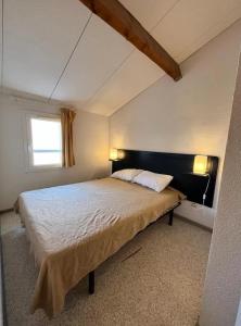 een slaapkamer met een groot bed en een raam bij Bel appartement avec place de parking privée, piscines in Vendres