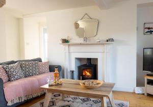 sala de estar con sofá y chimenea en Jasmine Cottage, sleeps 6 near Elie, with garden, en Fife