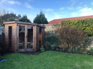 un invernadero de madera en el césped en un jardín en Jasmine Cottage, sleeps 6 near Elie, with garden, en Fife