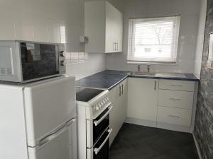 a white kitchen with white appliances and a window at Captivating 2-Bed Chalet in Great Yarmouth in Great Yarmouth