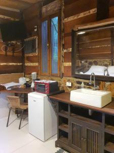 a kitchen with a sink and a counter with a microwave at Chalés Catavento in Maresias