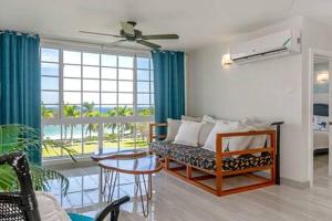 a living room with a couch and a large window at Ultra Modern 2BR Penthouse, Sleeps 5, Beach Front, Pool, Roof Patio, Montego Bay in Montego Bay