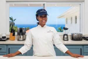 a chef standing in a kitchen with his arms crossed at Ultra Modern 2BR Penthouse, Sleeps 5, Beach Front, Pool, Roof Patio, Montego Bay in Montego Bay
