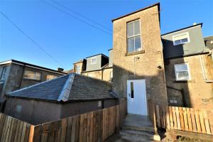 a house with a fence and a white door at Signature - No 5 Bonnet Apartments in Lanark