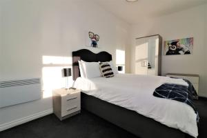 a bedroom with a large white bed with a black headboard at Signature - No 1 Bonnet Apartments in Lanark