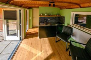 a kitchen with green walls and a chair in a room at Tinyhouse De Woord in Corle