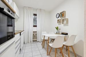 a white kitchen with white chairs and a table at DD_Homes LahnLiebe - Balkon, Therme, Smart TV in Bad Ems