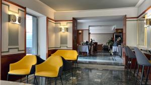 restauracja z żółtymi krzesłami i stołami w pokoju w obiekcie Hotel Centrale w mieście San Pellegrino Terme