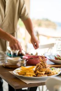 a person preparing food on a table with a plate of food at Trypiti Resort Blue Dream Palace and Hive Water Park in Limenaria