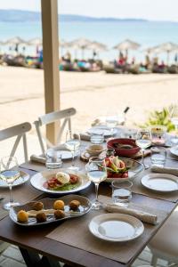 a wooden table with plates of food and wine glasses at Trypiti Resort Blue Dream Palace and Hive Water Park in Limenaria