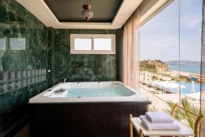 a bathroom with a tub with a view of the ocean at Trypiti Resort Blue Dream Palace and Hive Water Park in Limenaria