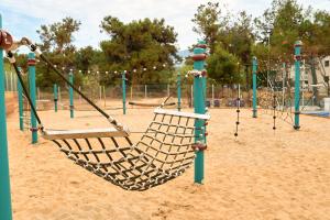 a swing set on a playground in the sand at Trypiti Resort Blue Dream Palace and Hive Water Park in Limenaria