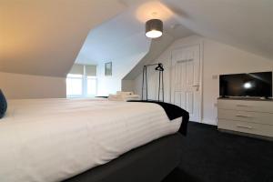 a bedroom with a large white bed and a tv at Signature - No 7 Bonnet Apartments in Lanark