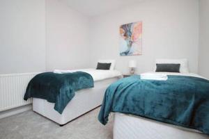 a bedroom with two beds and a painting on the wall at River View by Afan Valley Escapes in Port Talbot