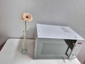 a flower in a vase next to a microwave at Yellow House - Duplex, Night view, White modern interior in Bucheon
