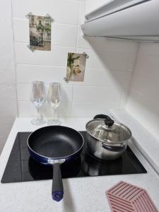 a pan on top of a stove with two wine glasses at Yellow House - Duplex, Night view, White modern interior in Bucheon