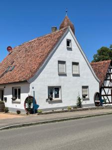 uma casa branca com um telhado vermelho numa rua em Ferienwohnung mit WiFi und 2 Schlafzimmern em Ipsheim