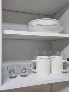 a shelf with cups and plates and bowls on it at Yellow House - Duplex, Night view, White modern interior in Bucheon