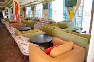 a room with many couches and tables and windows at The New Quill Hotel in Busia