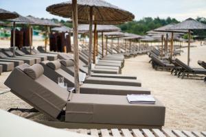 a row of lounge chairs and umbrellas on a beach at Trypiti Resort Blue Dream Palace and Hive Water Park in Limenaria