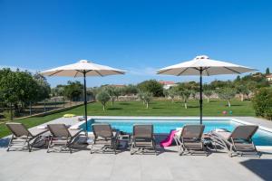 a group of chairs and umbrellas next to a swimming pool at Villa Arestea in Vodnjan