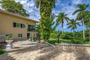 una casa con palmeras delante en Hospitality Expert McCartney - Tour Pool Bar Beach en Montego Bay