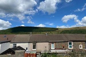 a brick house with a hill in the background at Taff Valley Cottage by StayStaycations in Merthyr Tydfil