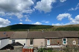 a brick house with a hill in the background at Taff Valley Heartwarming Cottage In Aberafan Merthyr Tydfil By STAE-Homes in Merthyr Tydfil