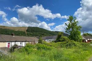 a house in the middle of a field of grass at Taff Valley Cottage by StayStaycations in Merthyr Tydfil