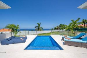 a swimming pool with two loungers and a swimming pool at Hospitality Expert Eden 7BR Pools Beach in Montego Bay