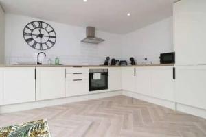 a large white kitchen with a clock on the wall at Treorchy Terrace by StayStaycations in Treorky