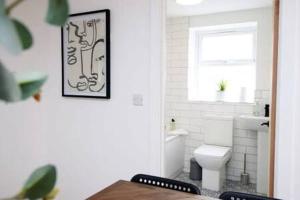 a white bathroom with a toilet and a window at Treorchy Terrace by StayStaycations in Treorky