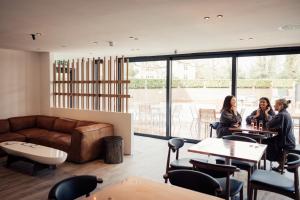 three people sitting at tables in a room with a couch at Talbooth House & Spa in Dedham