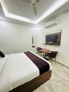 a bedroom with a bed and a desk and a tv at Hotel S R Palace Delhi Airport Unit BY URBAN Luxury in New Delhi