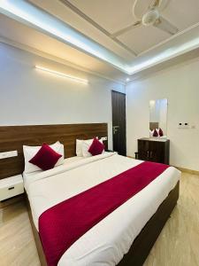 sypialnia z dużym łóżkiem z czerwonymi poduszkami w obiekcie Hotel S R Palace Delhi Airport Unit BY URBAN Luxury w Nowym Delhi